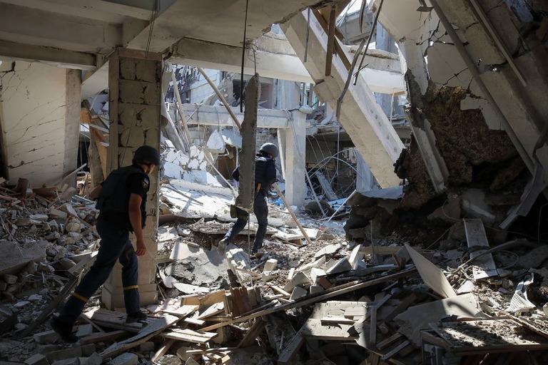 ロシアのミサイル攻撃によって損壊した教育大学の建物を調べる救急隊員ら/Vyacheslav Madiyevskyy/Reuters