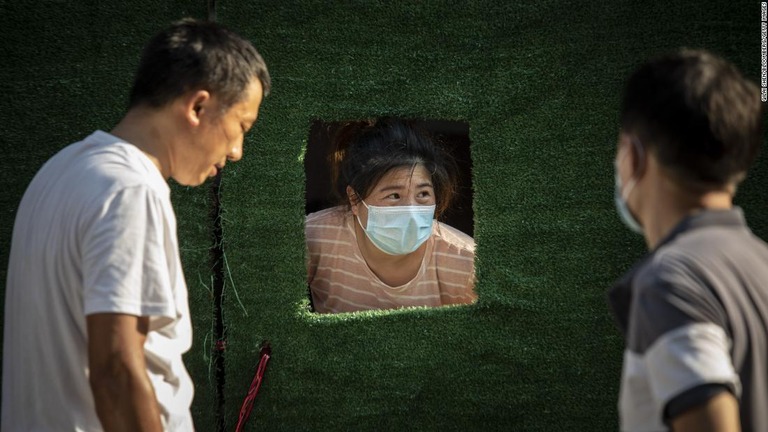 封鎖用バリケードの開口部からのぞく上海の住民＝１０日、中国・上海/Qilai Shen/Bloomberg/Getty Images