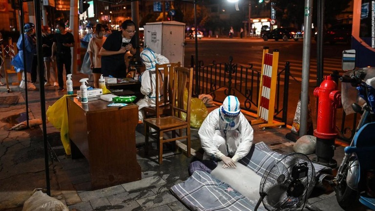 氷に手を置くなどして体を冷やす医療従事者＝１２日、中国・上海の新型コロナ検査場/Hector Retamal/AFP/Getty Images