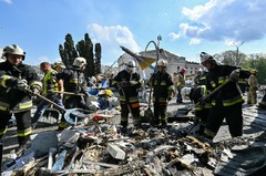 倒壊した建物のがれきをかき分ける消防士＝１４日