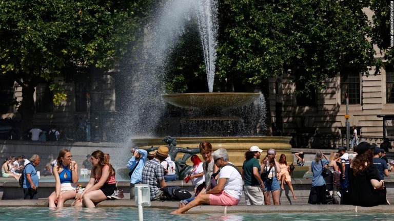 ロンドン中心部にあるトラファルガー広場の噴水のそばで涼む人々/Carlos Jasso/AFP/Getty Images