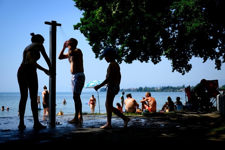 スイス・ローザンヌのレマン湖のほとりでシャワーを浴びて涼をとる人々＝６月１９日/Laurent Gillieron/Keystone/AP