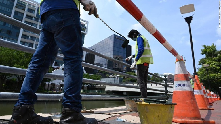 出稼ぎ労働者らは、暑い中でも屋外で重い防護服を着用し働いている＝シンガポール/Roslan Rahman/AFP/Getty Images