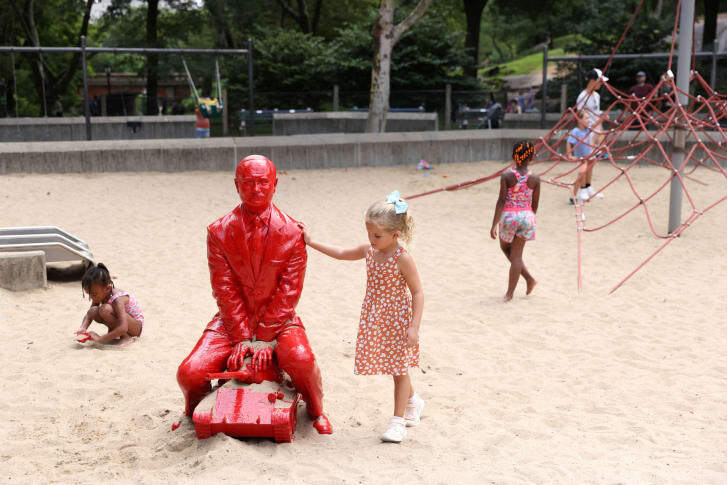 プーチン像の近くで遊ぶ子どもたち/Andrew Kelly/Reuters