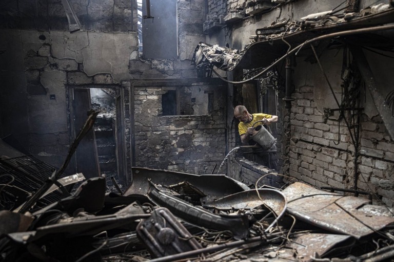 ドネツク州スラビャンスクで、ロシア軍の空爆を受けた建物の消火をしようとする男性