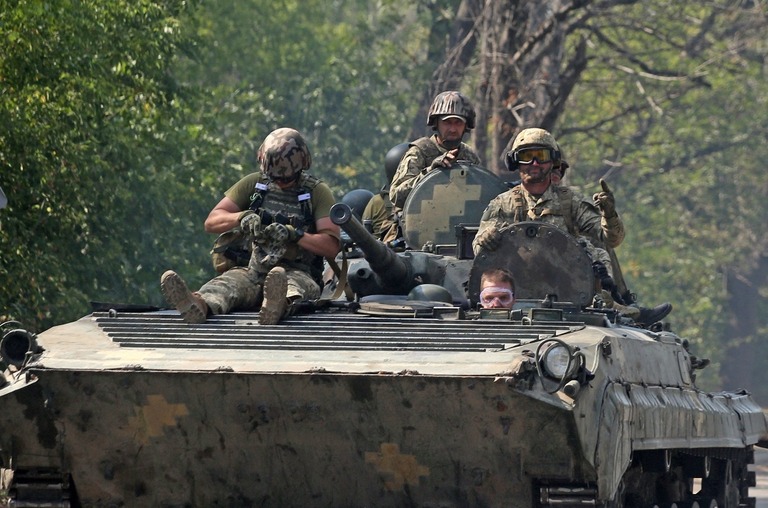 ドネツク州の道路を走行する歩兵戦闘車の上に座るウクライナ軍の兵士ら/Anatolii Stepanov/AFP/Getty Images