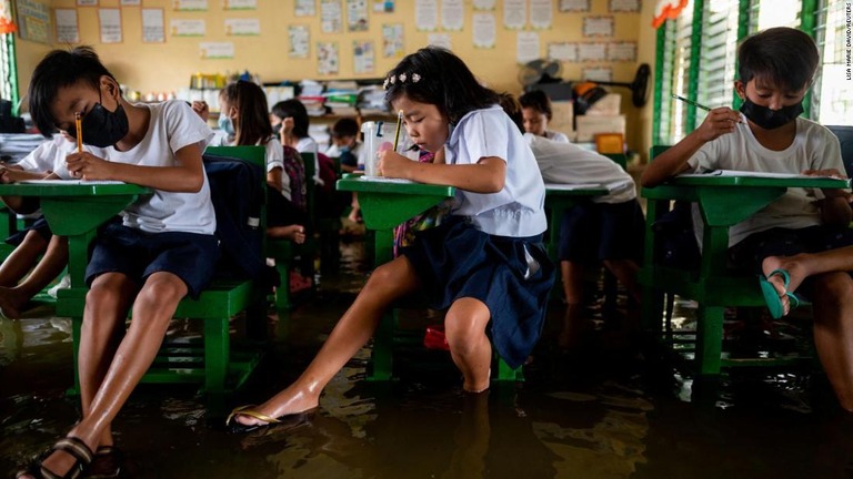 水浸しになった教室で授業を受ける生徒ら＝２２日、フィリピン・パンパンガ州/Lisa Marie David/Reuters