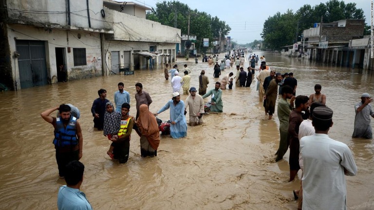 洪水により浸水したエリアを避難する人々＝２７日、パキスタン・ペシャワール/Hussain Ali/Anadolu Agency/Getty Images