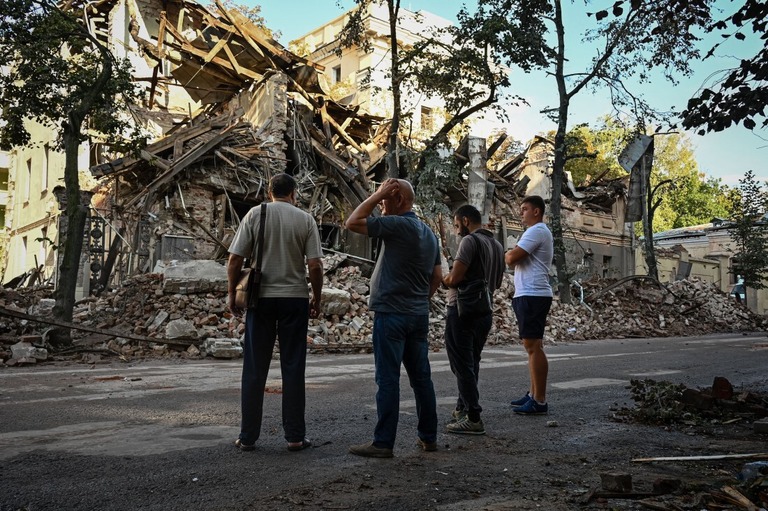 ハルキウへのミサイル攻撃後、破壊された建物の近くに立つ人々＝８月２９日、ウクライナ/Sergey Bobok/AFP/Getty Images