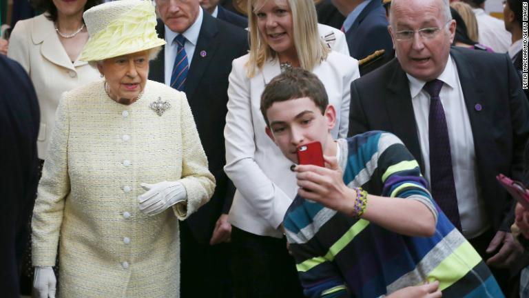 ２０１４年６月、北アイルランド・ベルファストで女王の前で自撮りする少年/Peter Macdiarmid/Getty Images