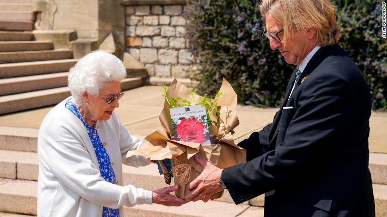 王立園芸協会のキース・ウィード会長（右）から、フィリップ殿下にちなんで「デューク・オブ・エディンバラ」と名付けられたバラを受け取る＝２０２１年６月/Steve Parsons/AP