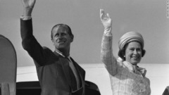 １９７５年５月、東京へ向かう飛行機から手を振るエリザベス女王（右）とフィリップ殿下