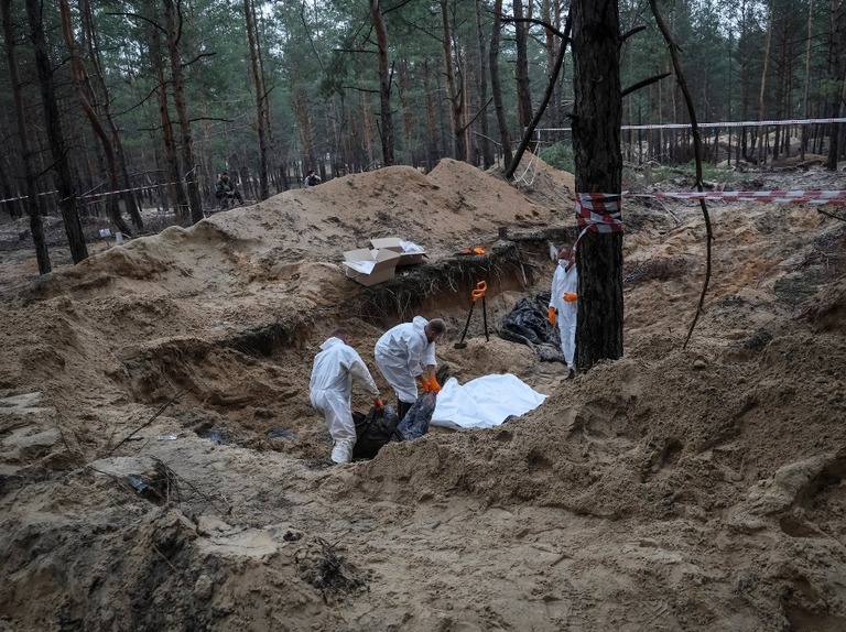 東部イジューム近郊の集団埋葬地で行われている掘り起こし作業の様子/Gleb Garanich/Reuters