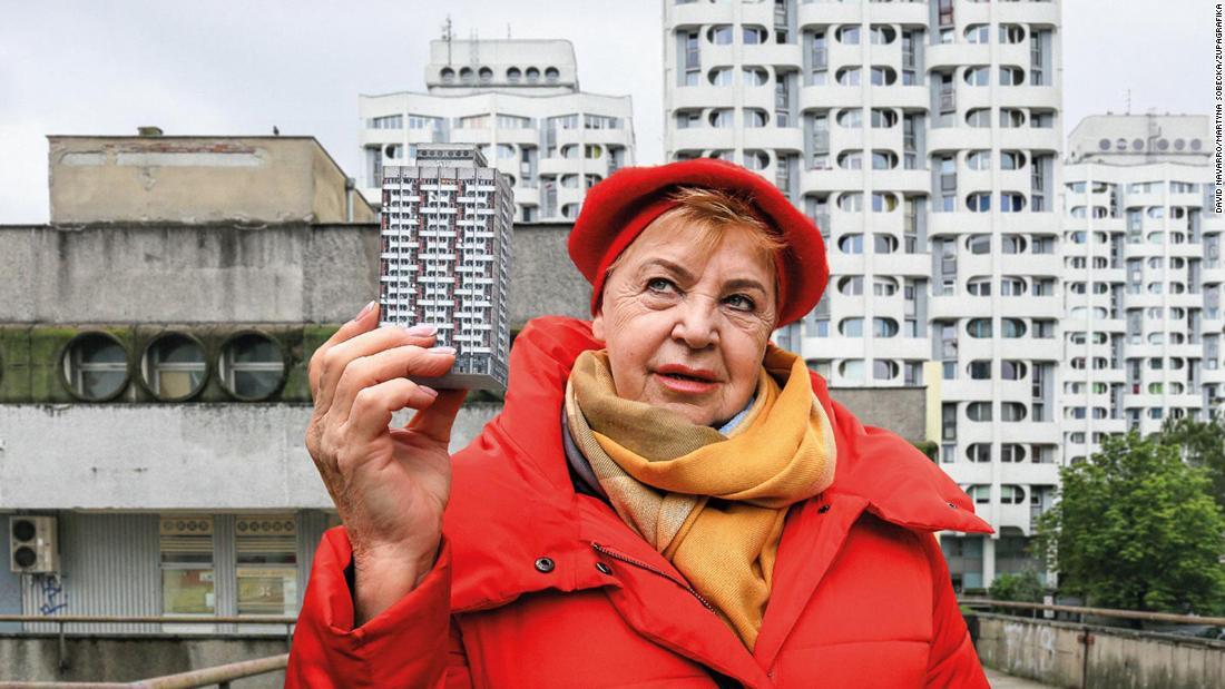 自らが暮らすソ連時代の団地の模型を手に、実際の建物と写真に収まるバーバラさん