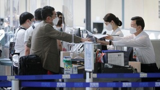 バンクーバー国際空港のカウンターで手続きを行う旅行者と職員