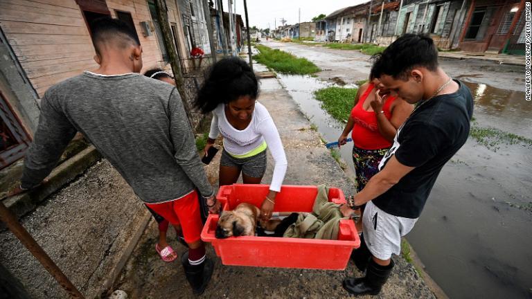 安全な場所に犬を運ぶ人々＝２６日、キューバ・バタバノ/Adalberto Roque/AFP/Getty Images