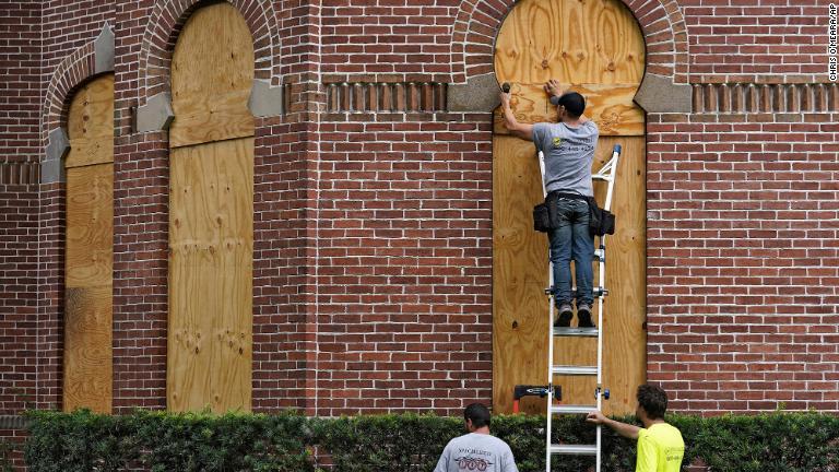 窓に板をはめ込む作業員＝２７日、米フロリダ州タンパ大学/Chris O'Meara/AP