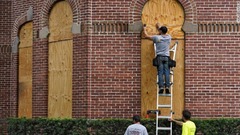 窓に板をはめ込む作業員＝２７日、米フロリダ州タンパ大学