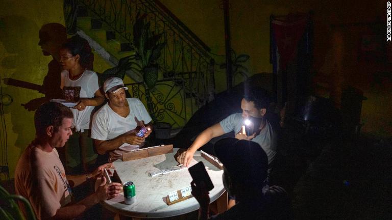 停電中に懐中電灯でドミノをする人々＝２８日、キューバ・ハバナ/Ramon Espinosa/AP