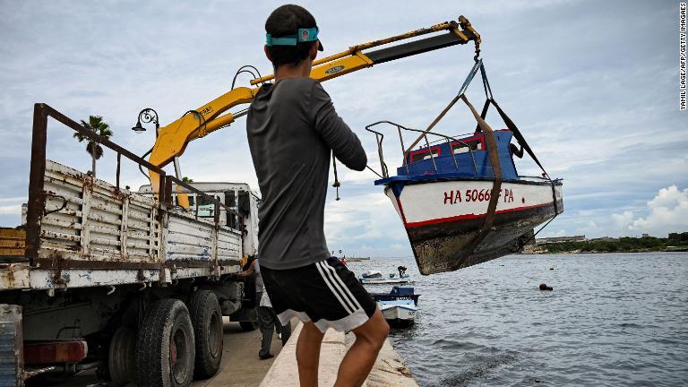 小型ボートを引き上げる男性＝２６日、キューバ・ハバナ湾/Yamil Lage/AFP/Getty Imagaes