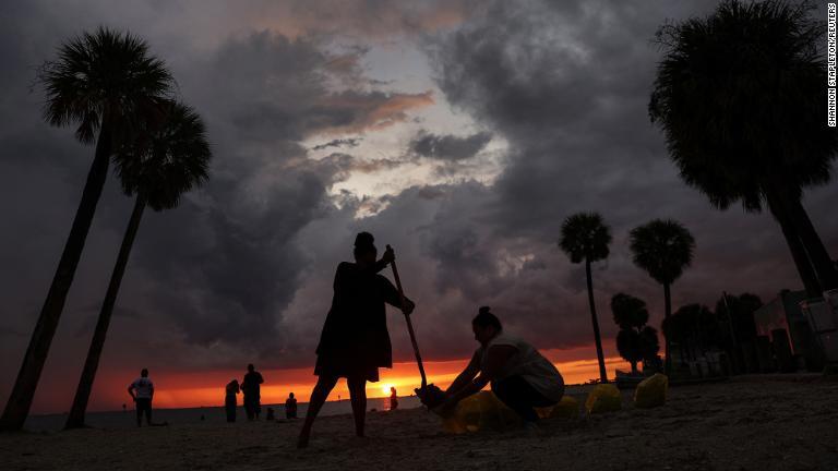 自宅周辺に土嚢（どのう）を埋める住民＝２６日、米フロリダ州タンパ/Shannon Stapleton/Reuters
