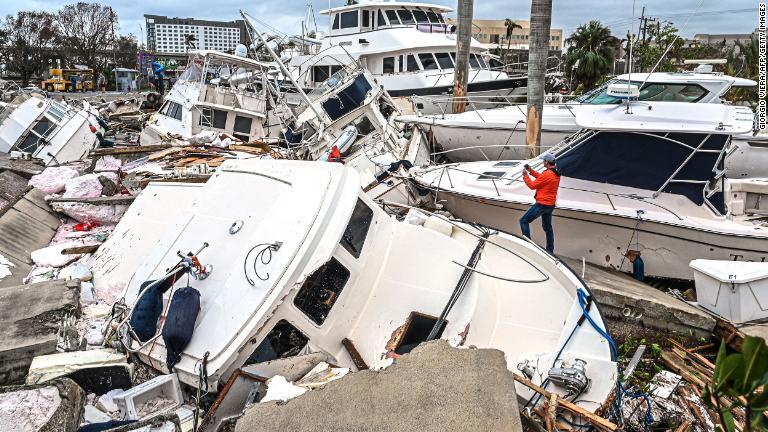 被害を受けたボートを撮影する男性＝２９日、米フロリダ州フォートマイヤーズ/Giorgio Viera/AFP/Getty Images