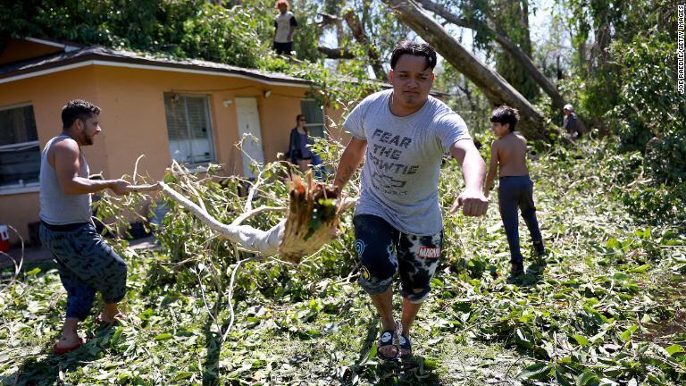 自宅から大木を運ぶ住民＝２９日、米フロリダ州フォートマイヤーズ/Joe Raedle/Getty Images