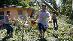 自宅から大木を運ぶ住民＝２９日、米フロリダ州フォートマイヤーズ