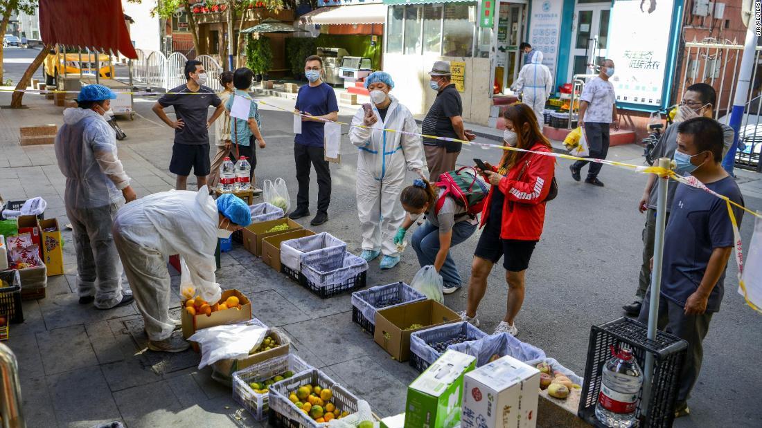 果物の露店の買い物客は規制線の外に立つ=5日、ウルムチ/Str/Reuters