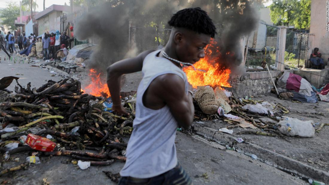 デモが行われる中、炎が上がるバリケード前を通る男性＝3日、ハイチ・ポルトープランス/Ralph Tedy Erol/Reuters
