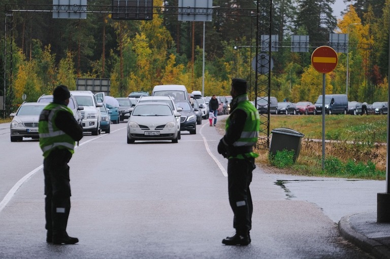 ロシア側から国境を越えて入ってくる車列を眺めるフィンランドの国境警備隊/Alessandro Rampazzo/AFP/Getty Images