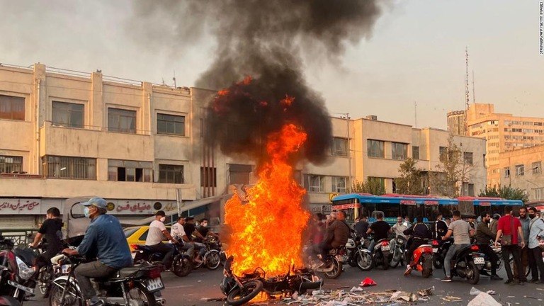 燃えるバイクの周りに集まった人々＝８日、イラン首都テヘラン/Stringer/AFP/Getty Images
