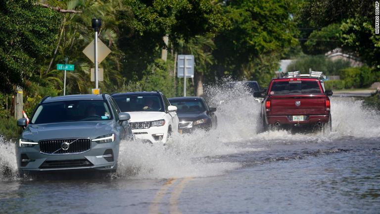 冠水した道路を通る車両＝１０日、米フロリダ州ポンパノビーチ/Wilfredo Lee/AP