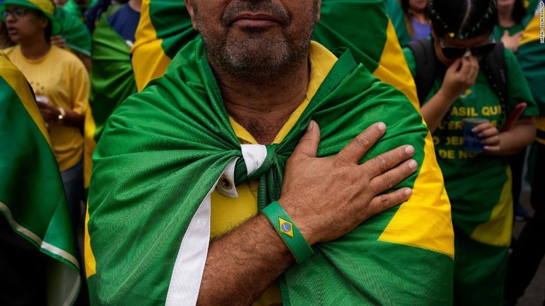 ブラジルの国旗を肩にかけて抗議を行うボルソナーロ大統領の支持者＝５日、ブラジル・サンパウロの軍事基地外/Matias Delacroix/AP