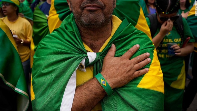 ブラジルの国旗を肩にかけて抗議を行うボルソナーロ大統領の支持者＝５日、ブラジル・サンパウロの軍事基地外/Matias Delacroix/AP