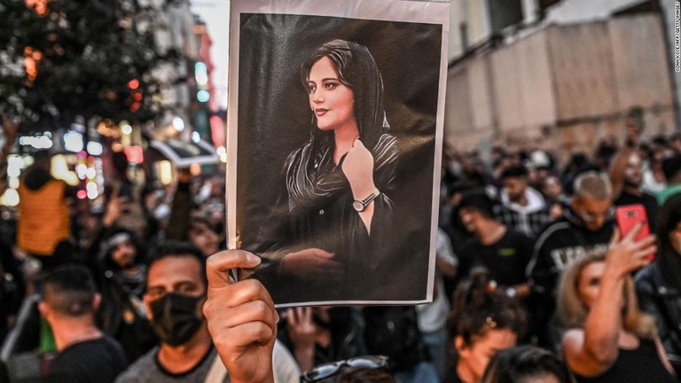 イランの風紀警察に拘束され死亡したクルド系女性の写真を掲げる抗議デモ参加者/Ozan Kose/AFP/Getty Images