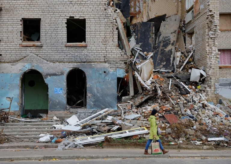 ヘルソン州ノバカホウカで崩れた建物の前を歩く人＝１０月３０日/Alexander Ermochenko/Reuters