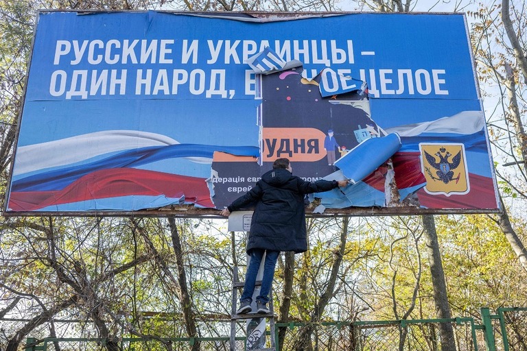 解放されたヘルソン市で、ロシアによる占領の時期に掲げられていた看板をはがす人/Bulent Kilic/AFP/Getty Images