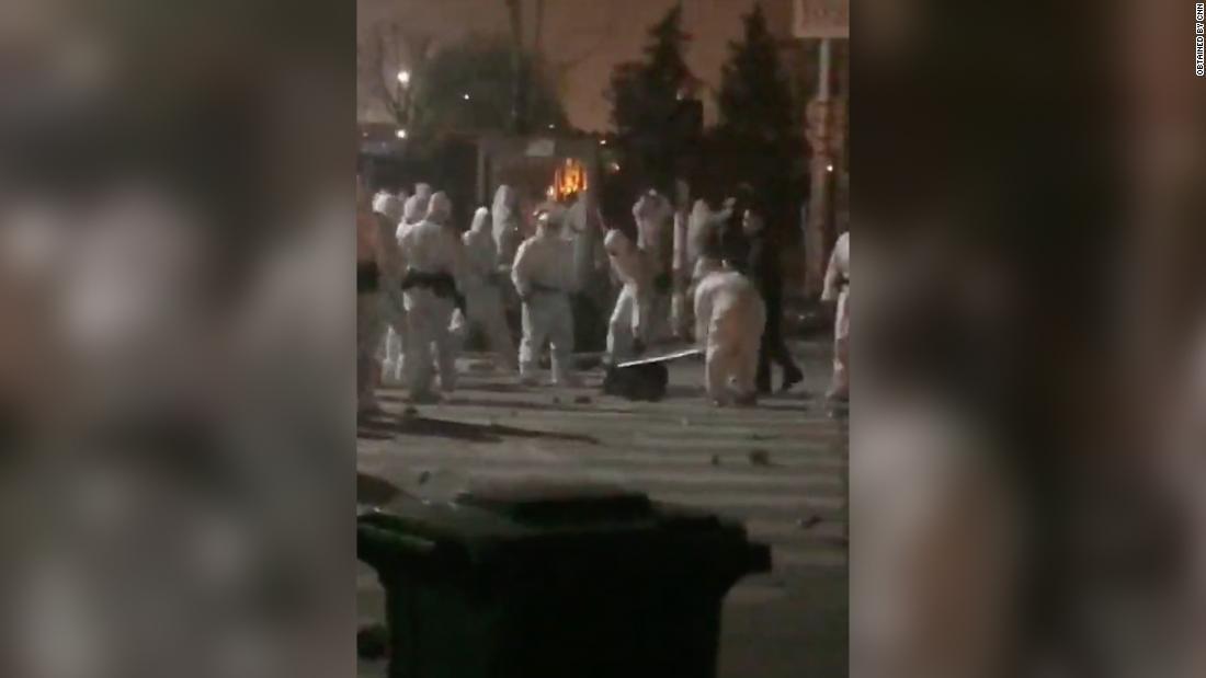 防護服を着た警官隊らが地面に横たわった労働者を蹴ったり殴ったりした様子が目撃された/Obtained by CNN