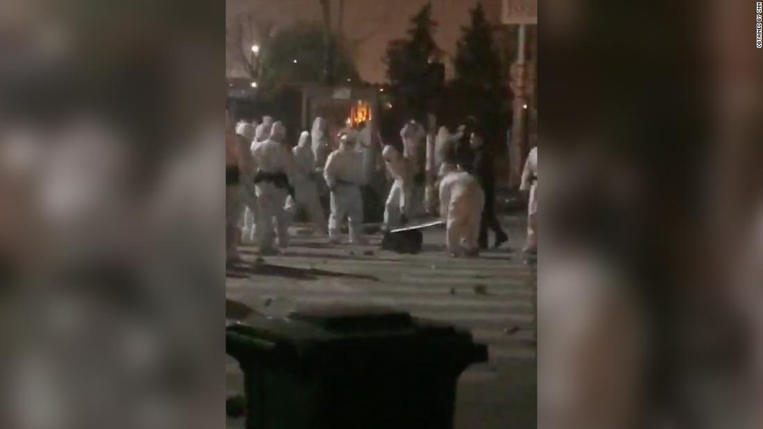 防護服を着た警官隊らが地面に横たわった労働者を蹴ったり殴ったりした様子が目撃された/Obtained by CNN