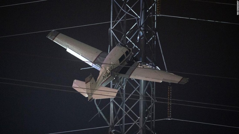 電線に衝突した小型機は、鉄塔に引っかかり約３０メートルの高さで宙づりになっていた/Tom Brenner/AP