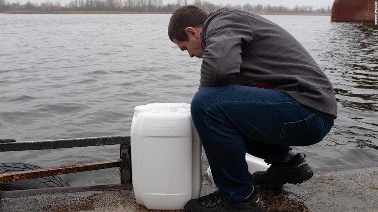 ドニプロ川で水を汲む男性。対岸はもうロシア側の占領地域だ/Mick Krever/CNN