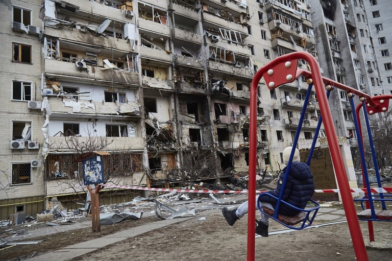 ミサイルの被害を受けた住宅の外でブランコに乗る子ども＝２月２５日、ウクライナの首都キーウ（キエフ）/Pierre Crom/Getty Images