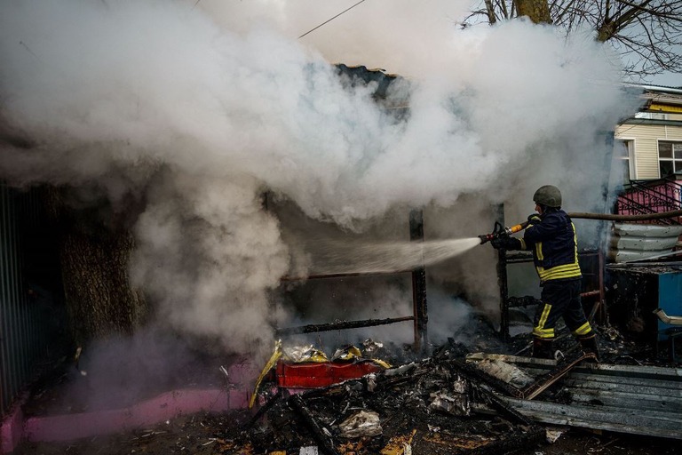 砲撃によって出火した店舗の消火作業にあたる消防隊員＝２４日、ウクライナ・ヘルソン/Dimitar Dilkoff/AFP/Getty Images