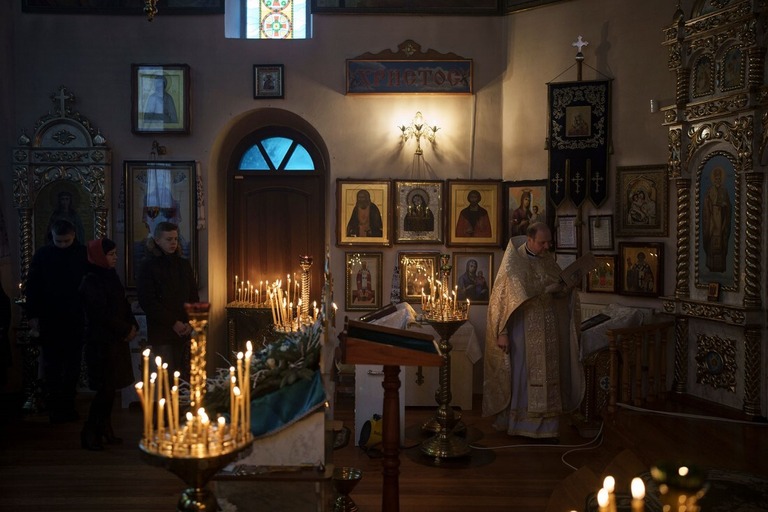 キーウ郊外の正教会教会でクリスマスミサに参加するウクライナ人ら＝２５日/Felipe Dana/AP