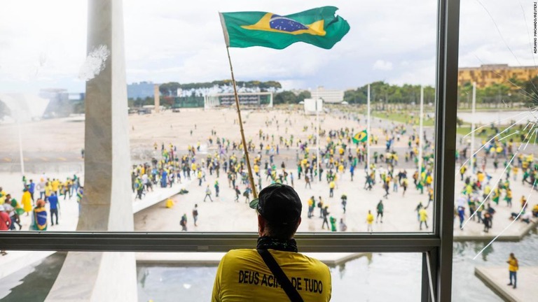 ブラジル国旗を掲げて抗議デモに参加するボルソナーロ前大統領の支持者/Adriano Machado/Reuters