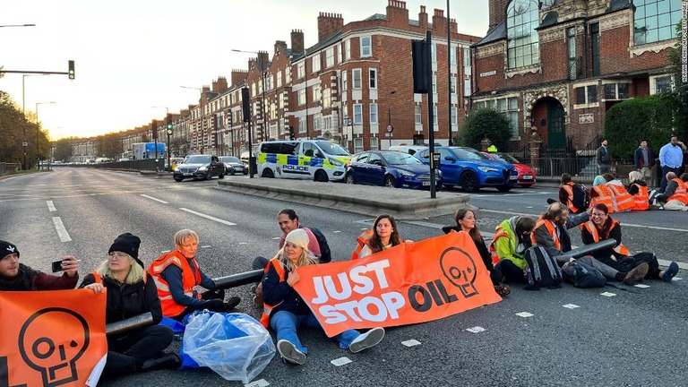 ロンドン西部の道路をふさいで横断幕を掲げる環境保護団体のメンバー/Adrian Dennis/AFP/Getty Images