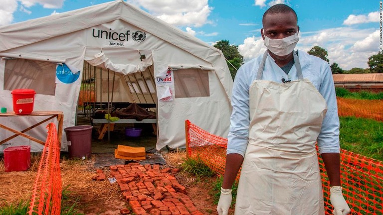 コレラ治療センターのテントの前に立つ医療関係者＝２０１８年２５日、マラウイ首都リロングウェ/AMOS GUMULIRA/AFP/AFP/Getty Images