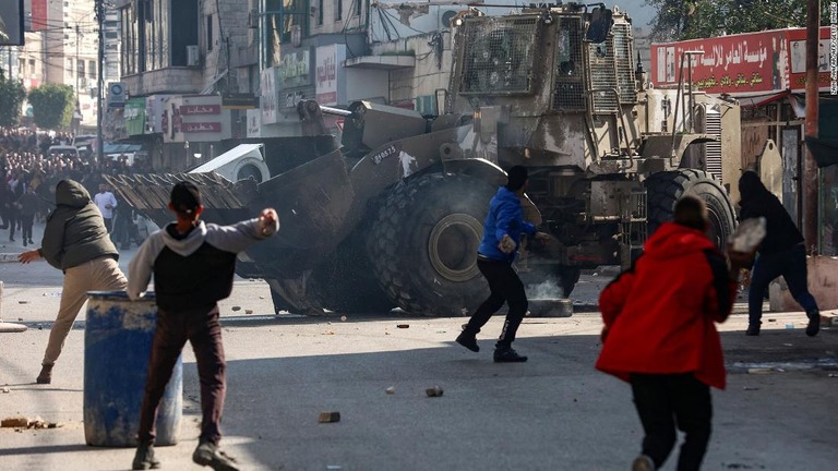 ヨルダン川西岸のジェニンでイスラエル軍のブルドーザーに投石するパレスチナ人＝２６日/Zain Jaafar/AFP/Getty Images