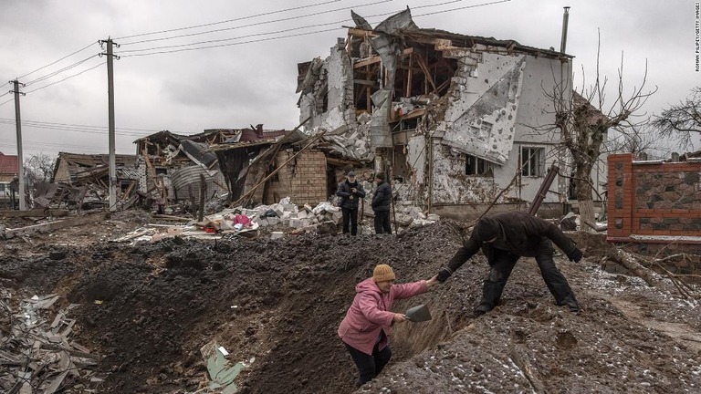 ロシア軍による攻撃を受けて損傷した建物の横にあるクレーターから出ようとする女性＝２６日、ウクライナ・キーウ郊外/Roman Pilipey/Getty Images